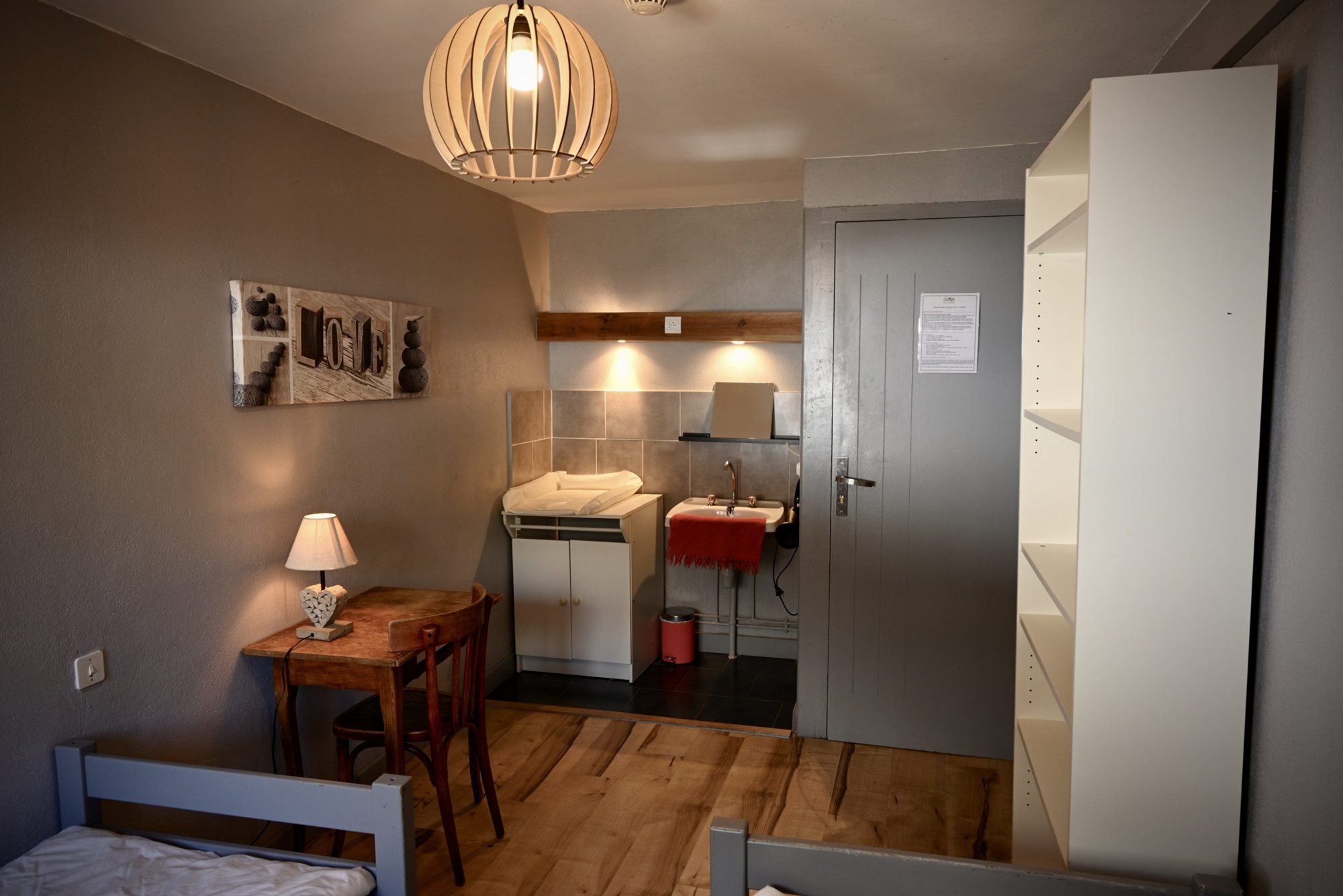 Chambre simple avec lits, bureau en bois et coin lavabo