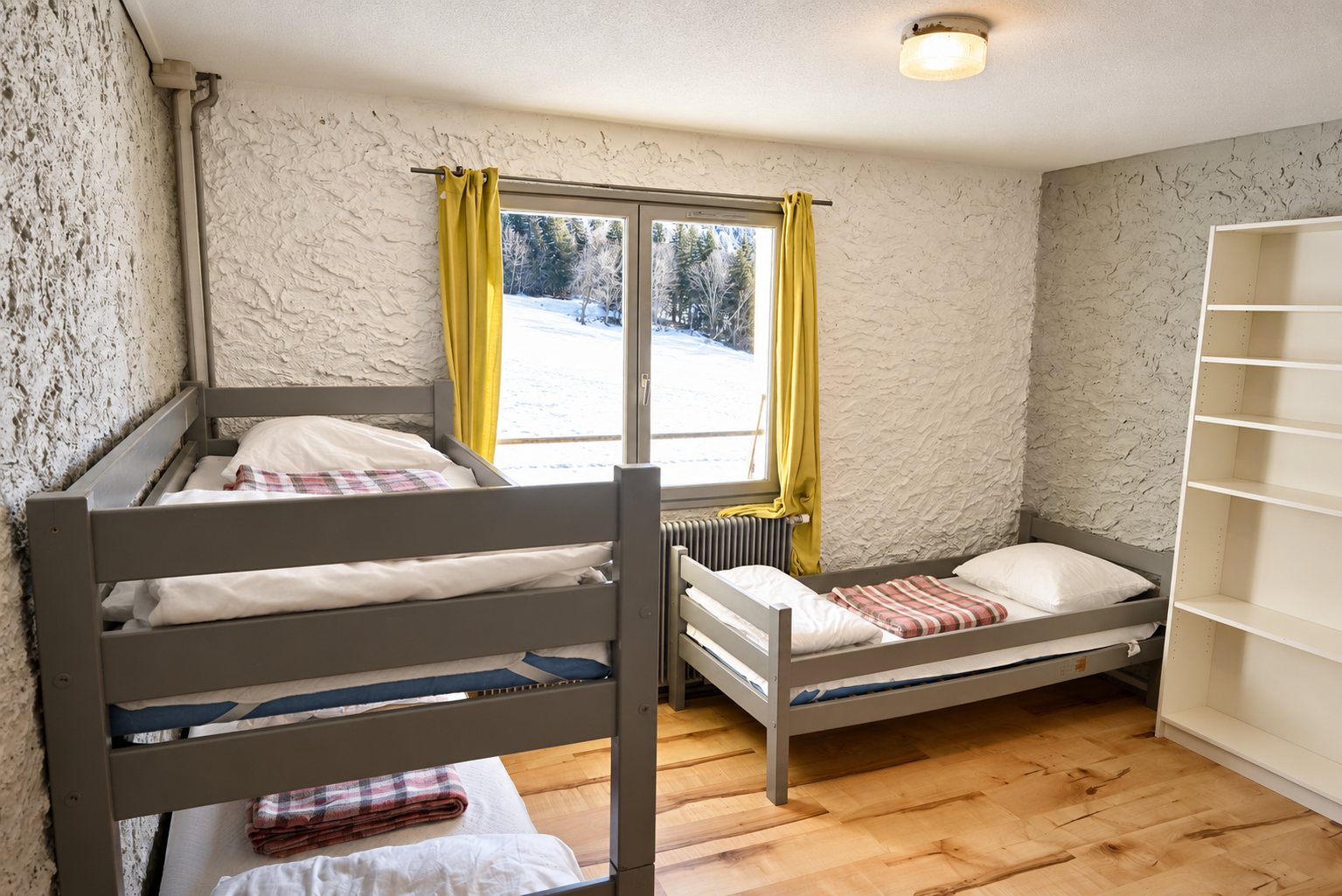 Chambre avec lits superposés et fenêtre donnant sur une forêt enneigée