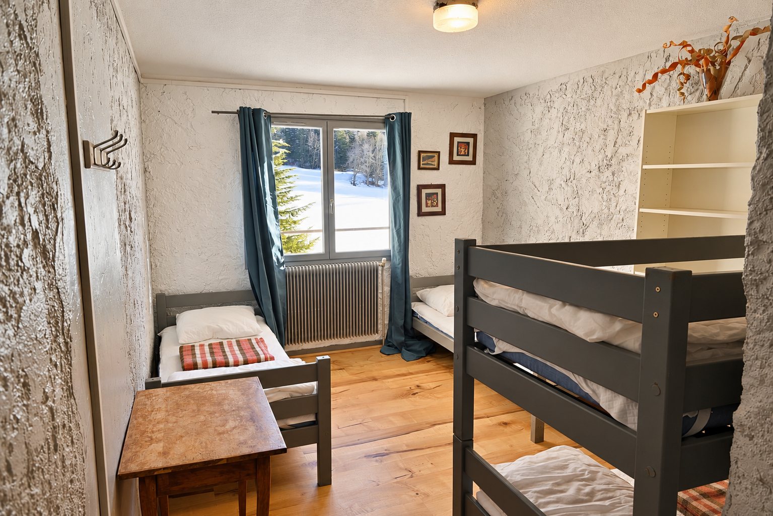 Chambre simple avec lits superposés et fenêtre donnant sur la neige