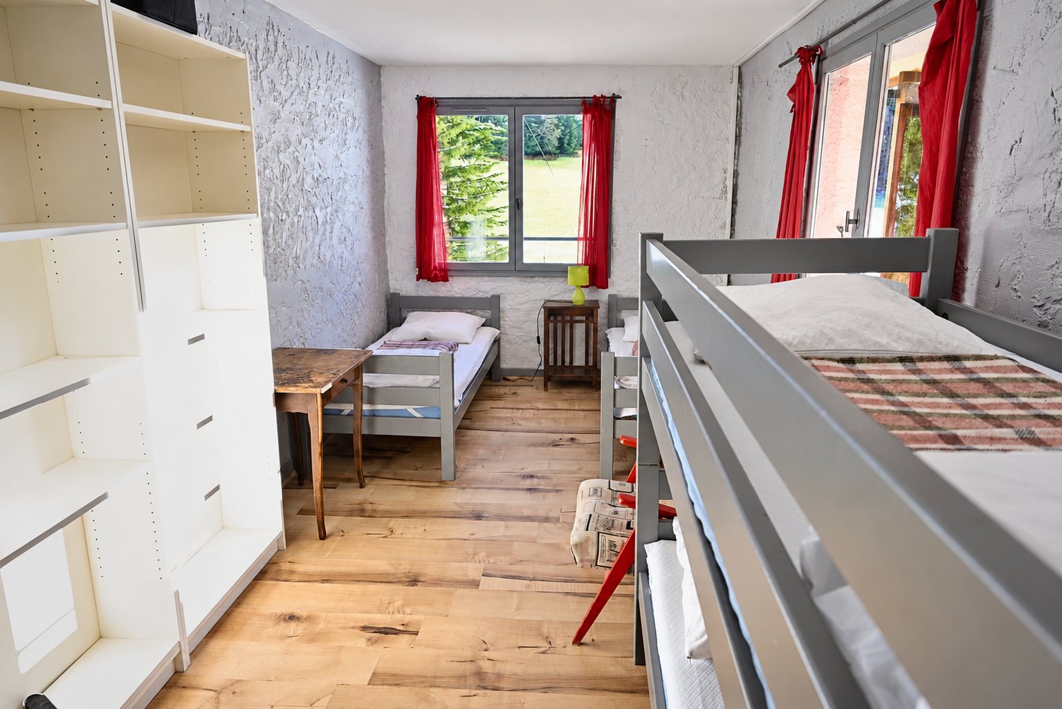 Chambre simple avec lits superposés, parquet clair et rideaux rouges
