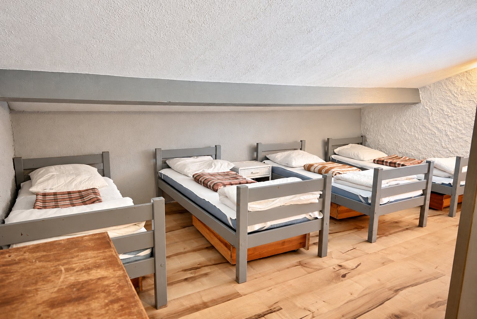 Dortoir mansardé avec cinq lits simples en bois gris
