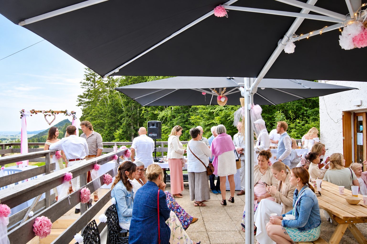 Invités d’un mariage sur la terrasse en bois du gîte, sous des parasols