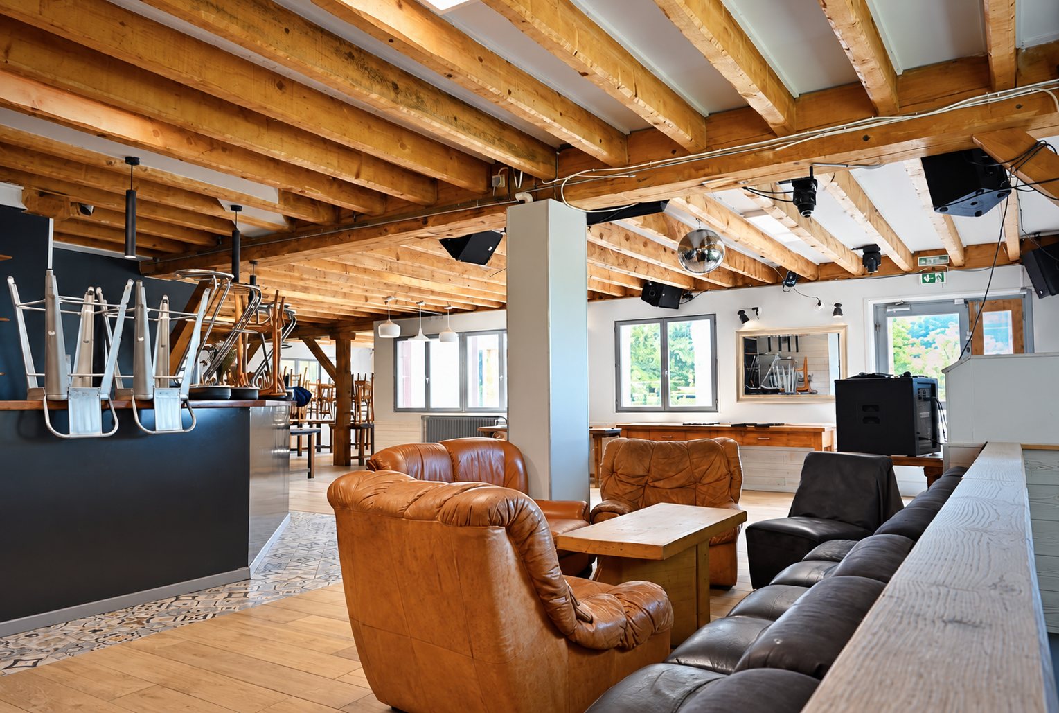 Salle avec bar, poutres apparentes et fauteuils en cuir